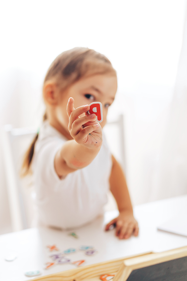 Little schoolgirl holding a letter while sitting at the table